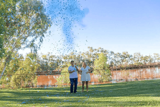 Blue confetti and smoke gender reveal by lake